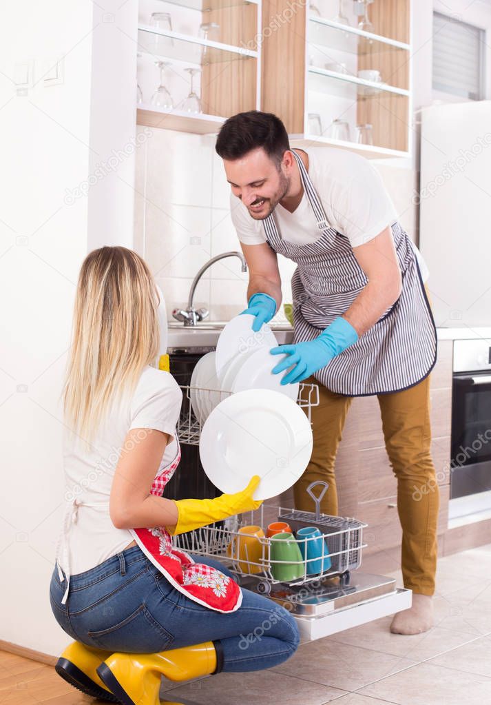 Happy couple unloading dishwasher