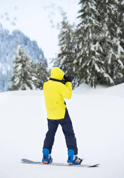 Junger Mann mit Fotokamera auf Snowboard — Stockfoto