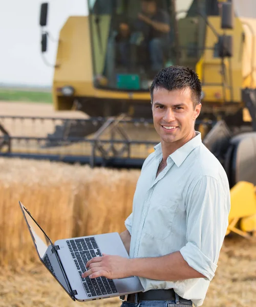 Agricultor con portátil en el campo durante la cosecha — Foto de Stock