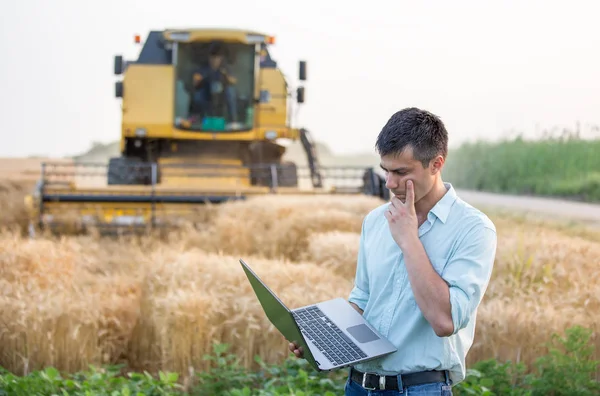 Ingenieur met laptop en combineren harvester — Stockfoto