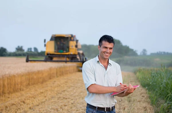 Engineer with notebook and combine harvester — Stock Photo, Image