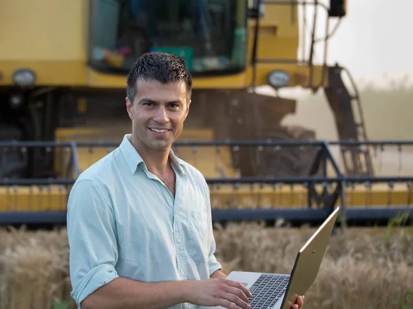 Engineer with laptop and combine harvester — Stock Photo, Image