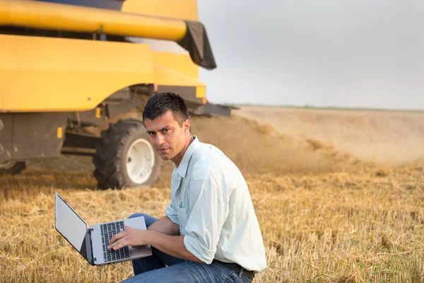 Engineer with laptop with combine harvester — Stock Photo, Image