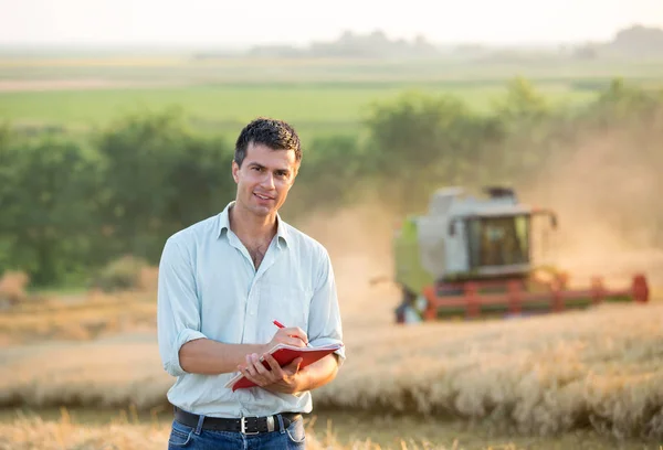 Ingegnere con notebook e mietitrebbia in campo — Foto Stock