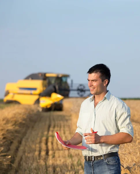 Engenheiro com notebook e colheitadeira em campo — Fotografia de Stock