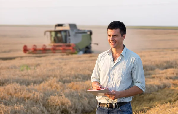 Ingenieur met laptop en combineren harvester in veld — Stockfoto