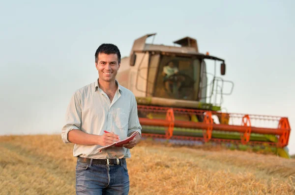 Engineer with notebook and combine harvester in field — Stock Photo, Image