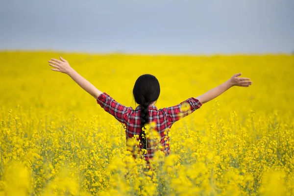 Chica con los brazos levantados en el campo de colza amarillo — Foto de Stock