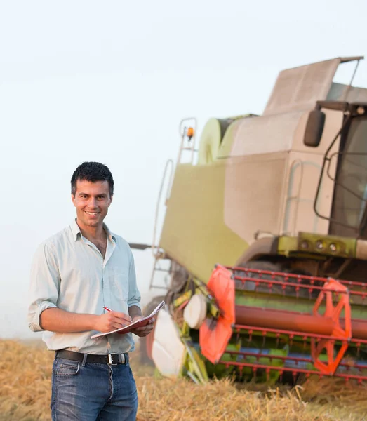 Engineer with notebook and combine harvester in field — Stock Photo, Image