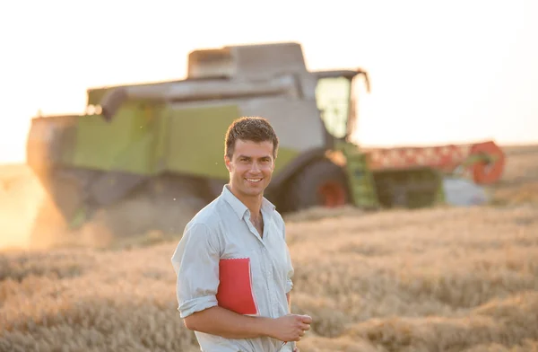 Ingeniero con cuaderno y cosechadora en campo — Foto de Stock