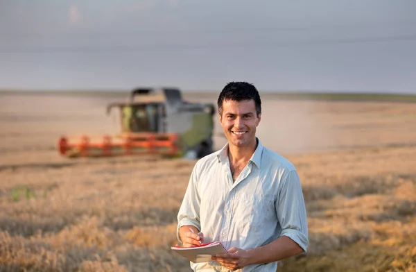 Engenheiro com notebook e colheitadeira em campo — Fotografia de Stock