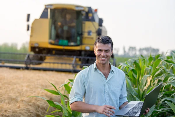 Engineer with laptop and combine harvester — Stock Photo, Image