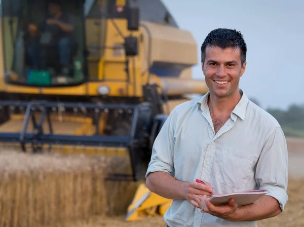 Ingenieur met laptop en combineren harvester in veld — Stockfoto