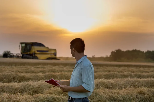 Ingenieur met laptop en combineren harvester in veld — Stockfoto
