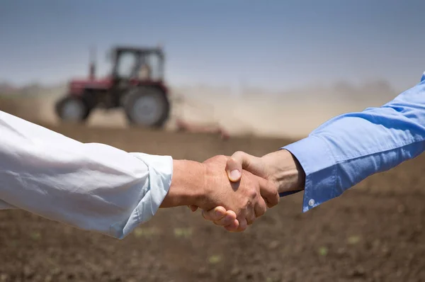 Les agriculteurs se serrent la main devant le tracteur — Photo