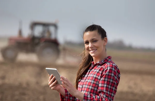 Boer vrouw met Tablet PC- en trekker in veld — Stockfoto