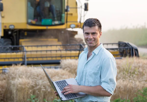 Glad Ung Landmand Ingeniør Med Laptop Stående Hvedemark Mens Mejetærsker - Stock-foto