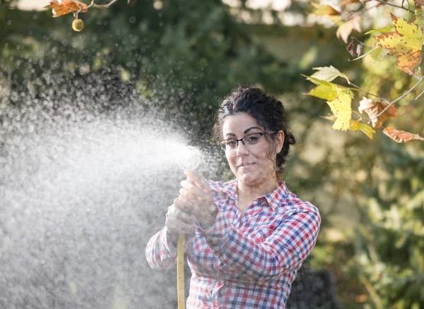 Девушка поливает растения из шланга — стоковое фото