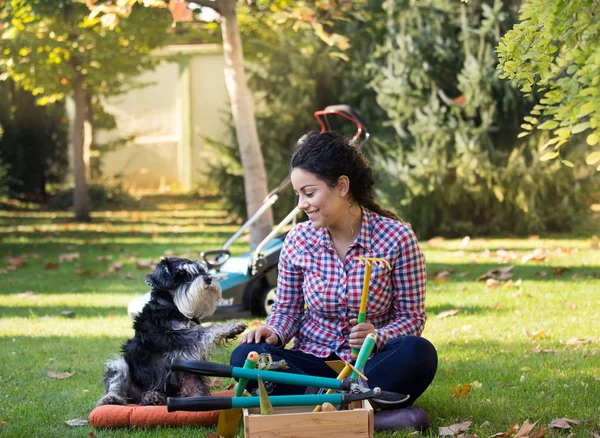 Kvinna och hund sitter på gräs i trädgården — Stockfoto