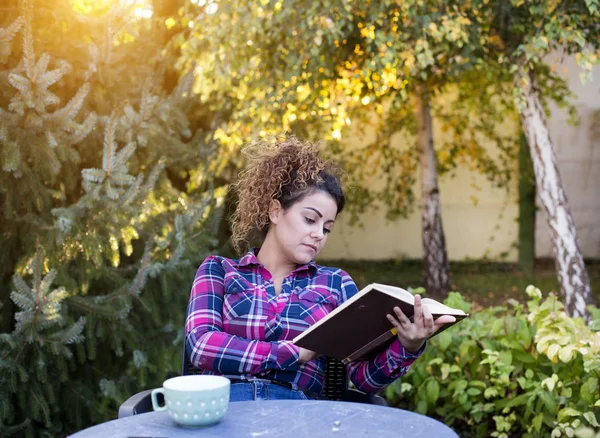 Flicka läsa bok och dricka te i parken — Stockfoto