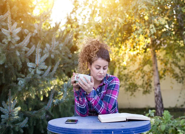 Mädchen liest Buch und trinkt Tee im Park — Stockfoto