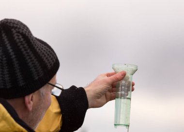 Farmer holding rain gauge in field