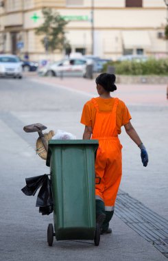 Garbage worker pulling trash can in street