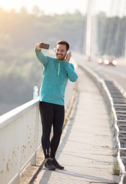 Jogger taking selfie on bridge