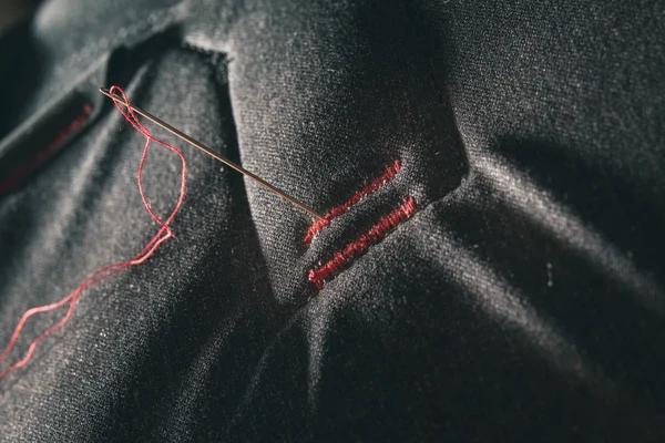 Červená nit na šedém textilním — Stock fotografie
