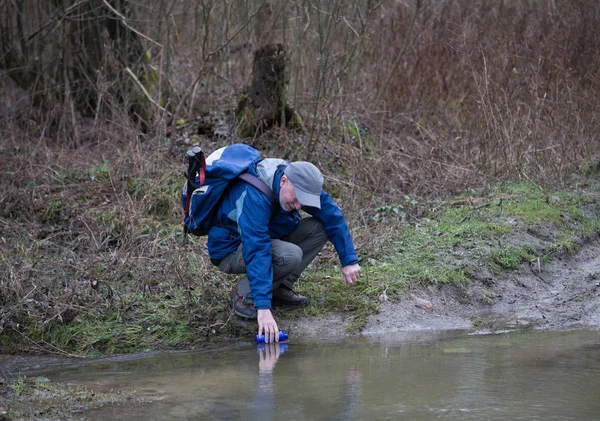 Hiker picking water from river — ストック写真