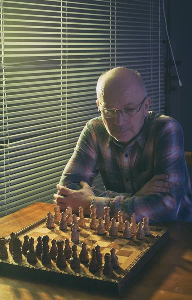 Homem jogando xadrez ao lado de janelas cortinas wtih — Fotografia de Stock