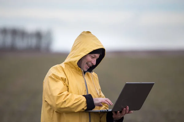 Agricultor con portátil en el campo en el día frío —  Fotos de Stock