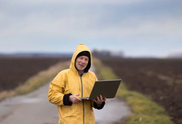 Agricoltore con laptop in campo nelle giornate fredde — Foto Stock