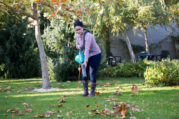 裏庭で季節の作品のための葉のブロワーを使用してかなり若い女性 — ストック写真