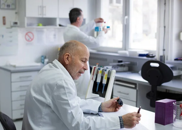 Biologo Maturo Che Scrive Note Sulla Ricerca Laboratorio Mentre Collega — Foto Stock