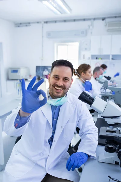Biólogo Satisfeito Mostrando Sinal Frente Sua Equipe Laboratório — Fotografia de Stock