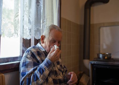 Yaşlı adam mendil tutuyor ve burnunu siliyor. Virüs ve grippe kavramı