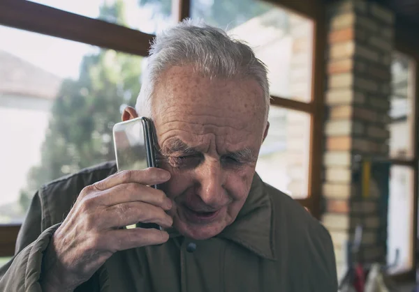老人は家の前で携帯電話で話している — ストック写真