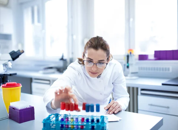 実験室の試験管でサンプルを扱う若い女性生物学者 — ストック写真