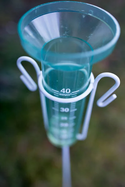 Close up of plastic rain gauge in field. Measuring equipment for rainfall quantity in field
