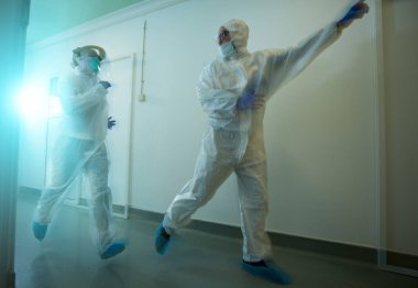 Koridorda kostümü giymiş iki biyolog koşuşturuyor. Acil durum ve kirlilik kavramı