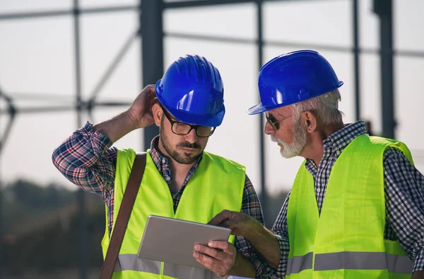 Dois Engenheiros Experientes Olhando Para Tablet Canteiro Obras Com Estrutura — Fotografia de Stock