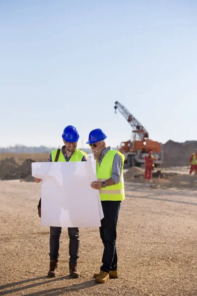 Dwóch Doświadczonych Inżynierów Przygląda Się Planom Rozmawia Placu Budowy Metalowym — Zdjęcie stockowe