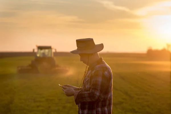 Agricultor Olhando Para Tablet Campo Frente Trator Fundo Pôr Sol — Fotografia de Stock