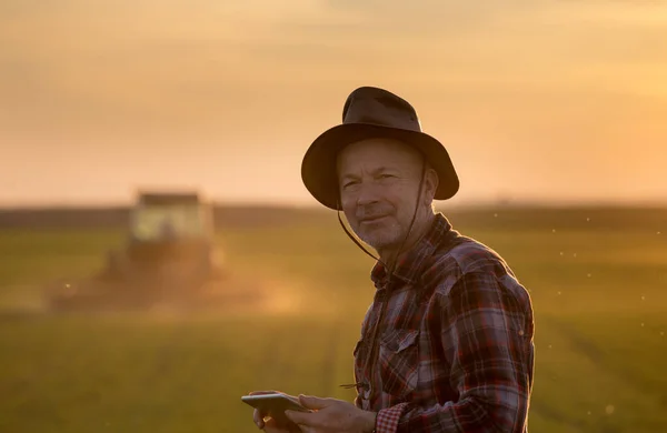 Retrato Agricultor Senior Con Sombrero Sosteniendo Tableta Delante Del Tractor —  Fotos de Stock