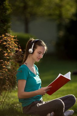 Arka bahçede çimenlerde oturan ve bahar aylarında salgın hastalık izolasyonu sırasında online okula giden kız.