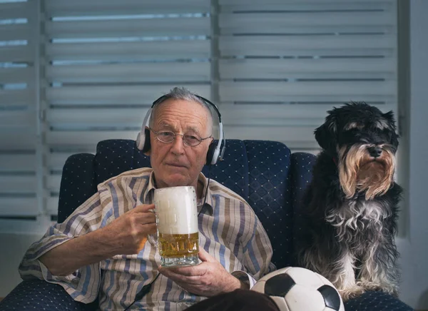 Старший Чоловік Собакою Сидить Кріслі Вдома Тримає Футбольний Кухоль Пива — стокове фото