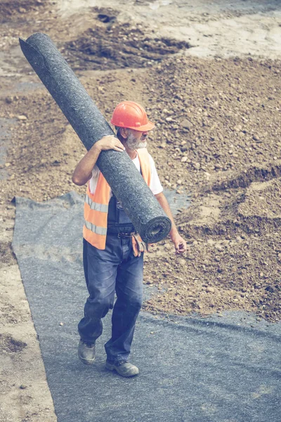 Worker carrying roll of geotextile insulation 3 — Stock Photo, Image