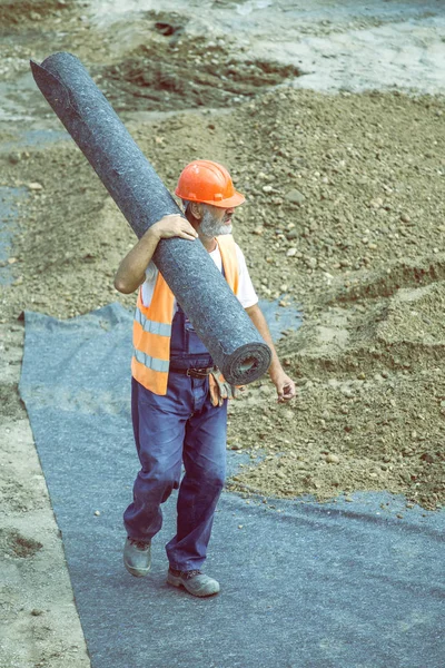 Geotekstil yalıtım 4 rulo taşıyan işçi — Stok fotoğraf