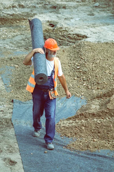 ジオテキ スタイル断熱材 4 のロールを運ぶ労働者 — ストック写真